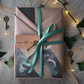 Mystery Moment – Livre mystère emballé façon kraft surprise, avec ruban satin vert, ambiance forêt et touches mystiques